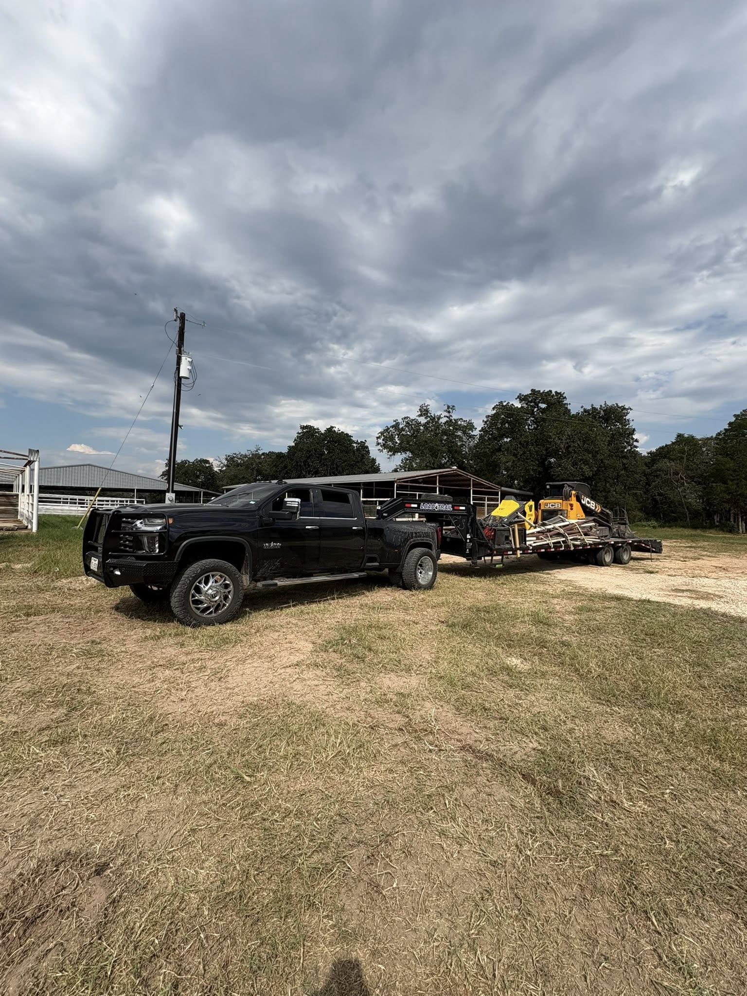 Truck and trailer transporting mini excavator to job site